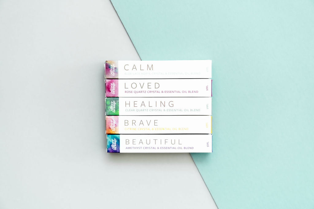 5 boxed roller bottles with their names showing on an aqua and white backdrop