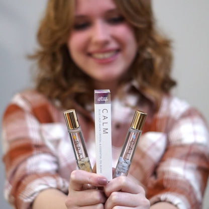 Person holding three small bottles with visible text, against a neutral background