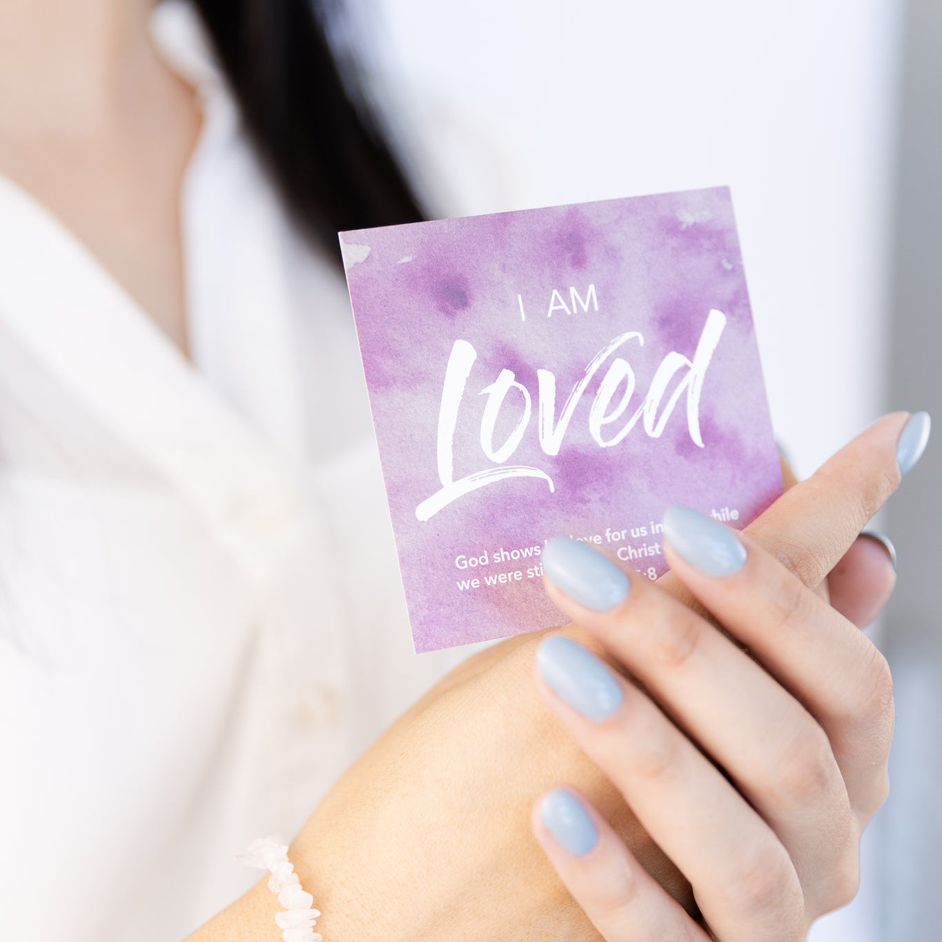 Hand holding a card with 'I AM Loved' text against a blurred background