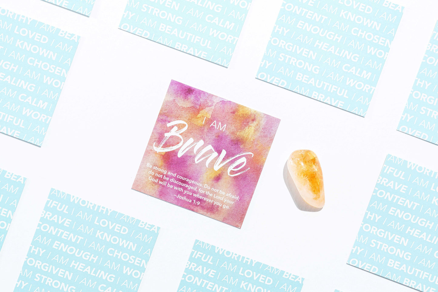 A Brave Affirmation card with scripture bible vers and a citrine stone with other cards flipped over on a white backdrop