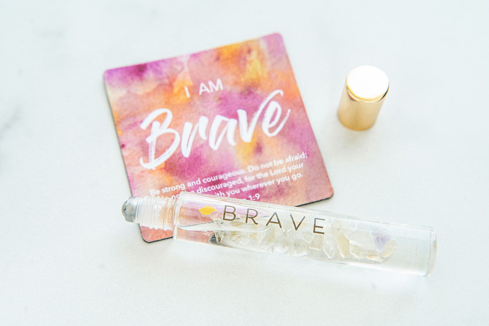 Roll-on bottle labeled 'Brave' with a colorful card reading 'I am Brave' on a light background