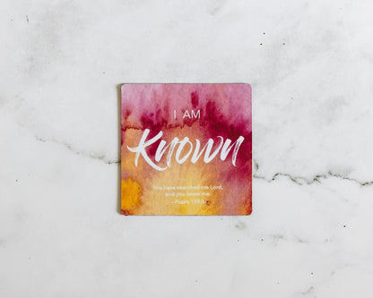 A Red and yellow christian magnet that says I Am Known with a bible verse from Psalm 139:1 on a white marble background that says You have searched me Lord and you know me.