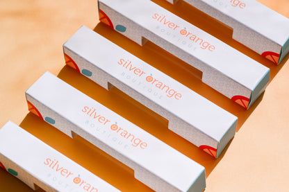 5 Branded Boxes for Roller bottles that say Silver Orange Boutique with logo on pale orange backdrop