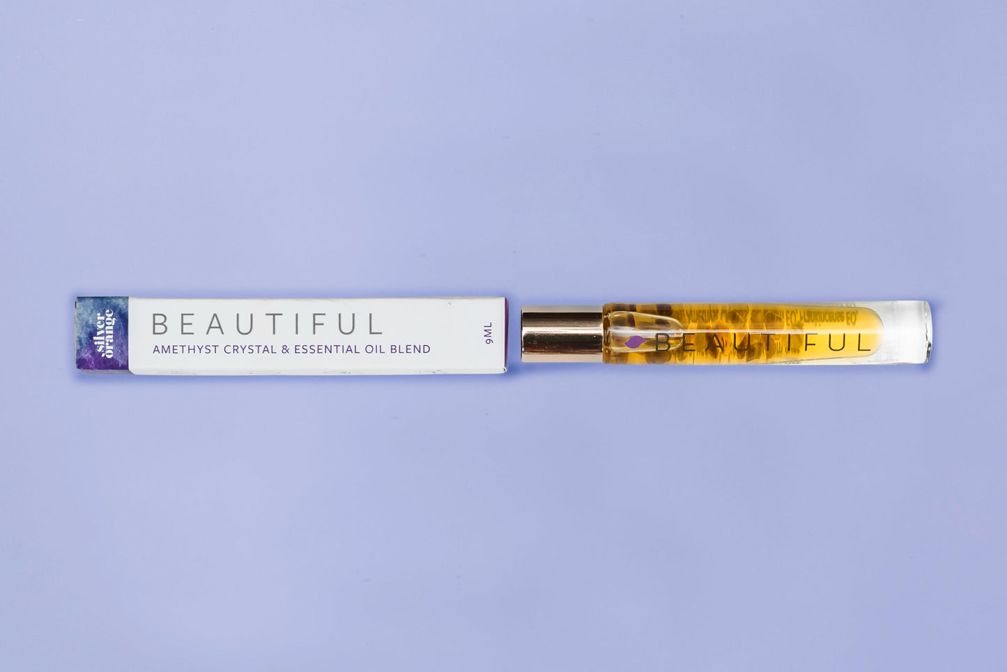Roll-on bottle with essential oil blend labeled 'Beautiful' on a purple background