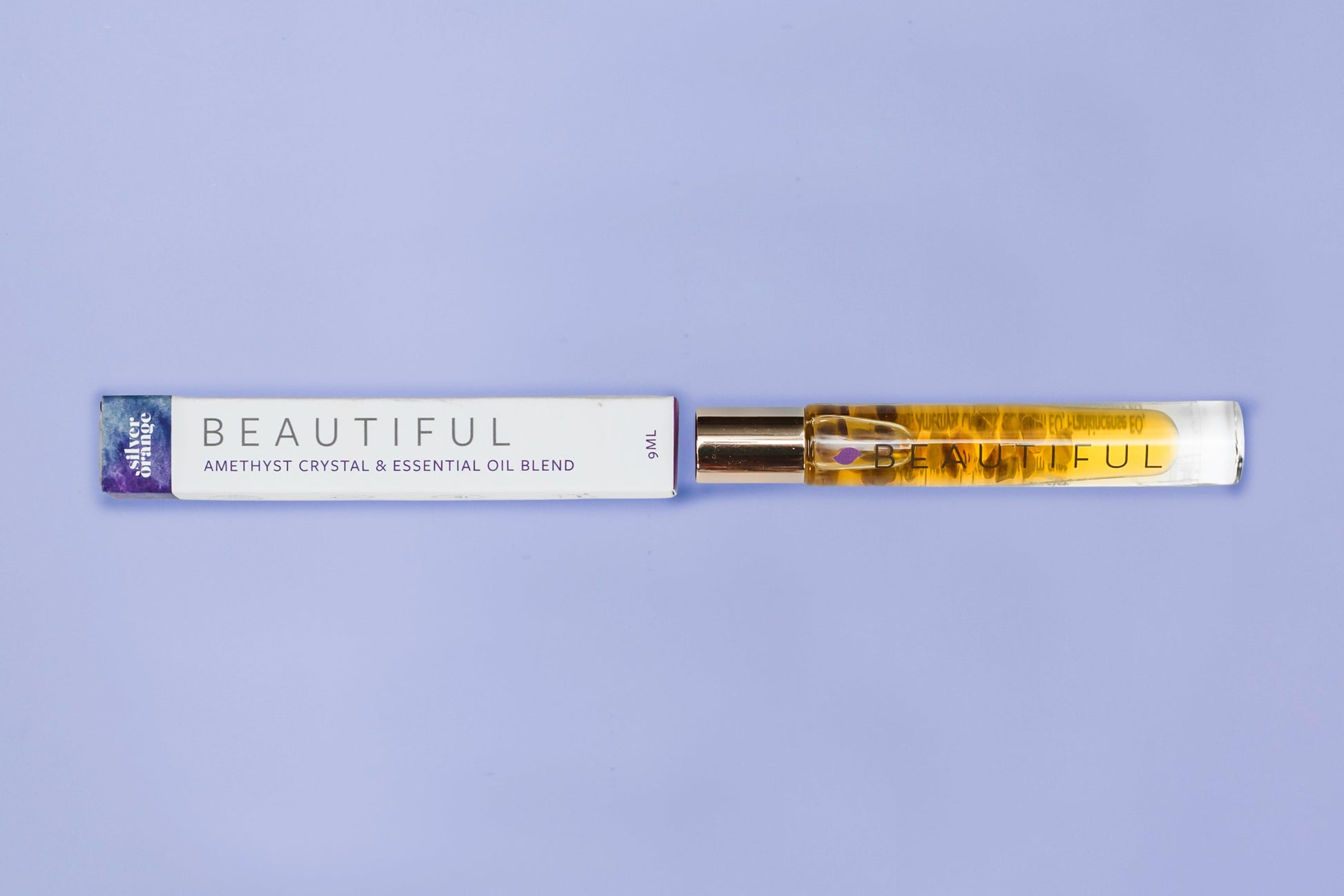Roll-on bottle with essential oil blend labeled 'Beautiful' on a purple background