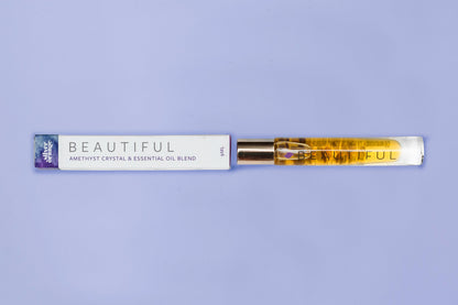 Roll-on bottle with essential oil blend labeled 'Beautiful' on a purple background