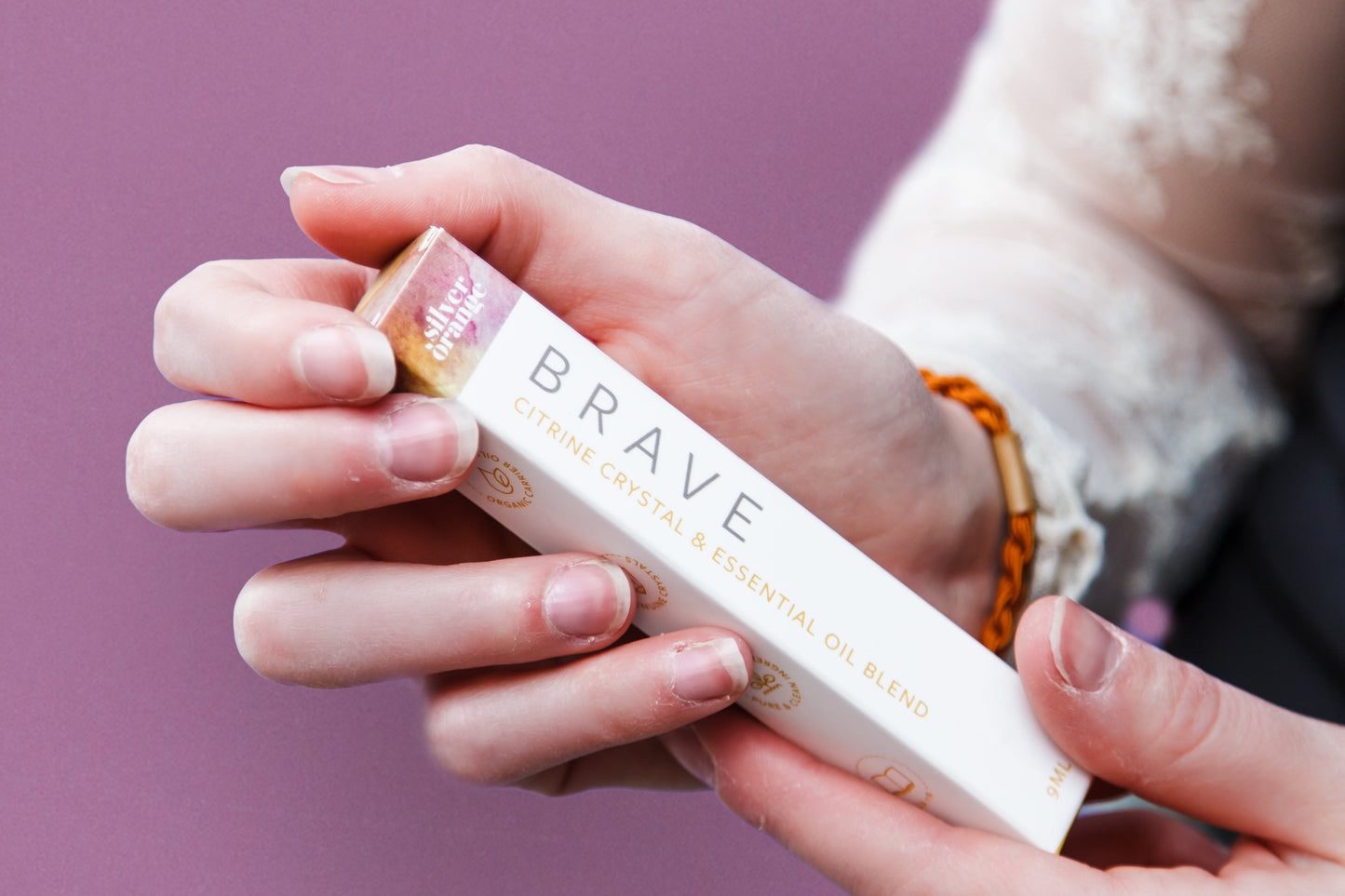Person holding a product labeled 'Brave' against a purple background