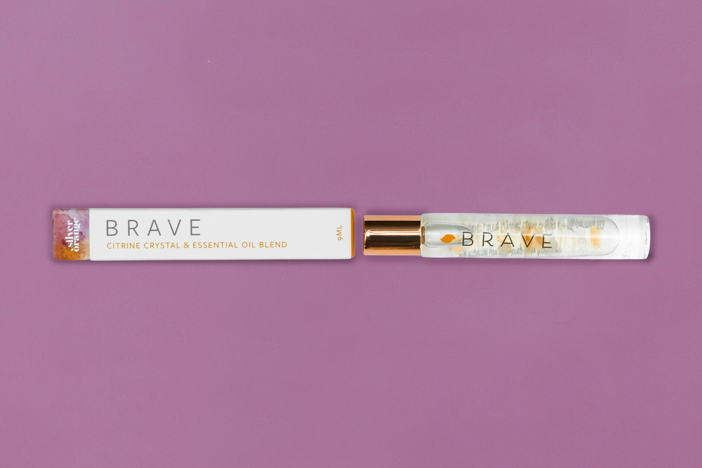 Roll-on bottle and packaging of 'Brave' essential oil blend on a purple background