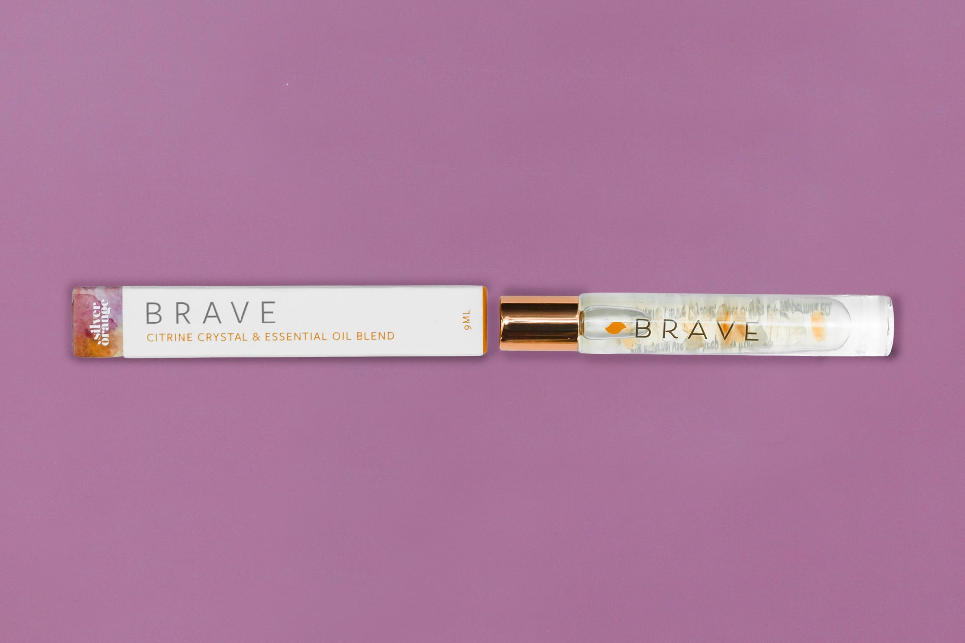 Roll-on bottle and packaging of 'Brave' essential oil blend on a purple background