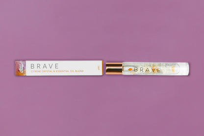 Roll-on bottle and packaging of 'Brave' essential oil blend on a purple background