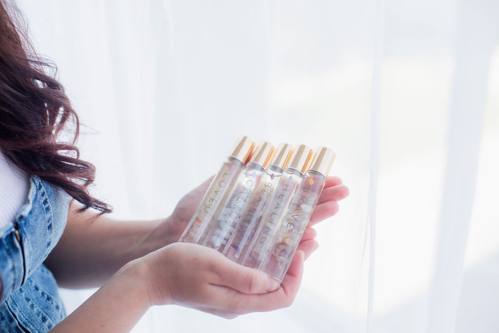 A woman holding 5 crystal roller bottles