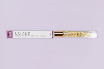 Roll-on bottle labeled 'LOVED' with a purple cap on a light gray background